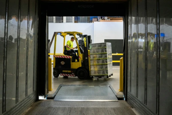 A forklift loading a pallet of boxes photographed from inside a trailer