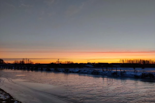 Sunrise on a snowy landscape with a frozen canal