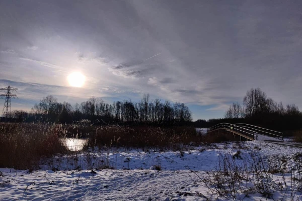 Snowy field with a bridge and cloudy sunrise