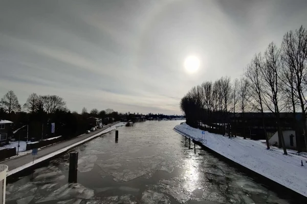 Low sun with a halo seen from a bridge (Doenbrug) over the Schie canal with some ice in it.