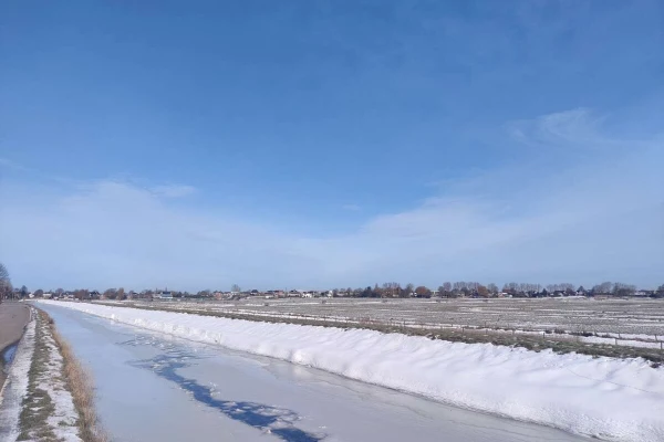 Snow and ice in a crop field with a small canal