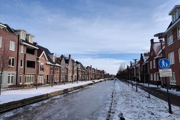 People skating on ice on a canal between residential buildings in Berkel en Rodenrijs