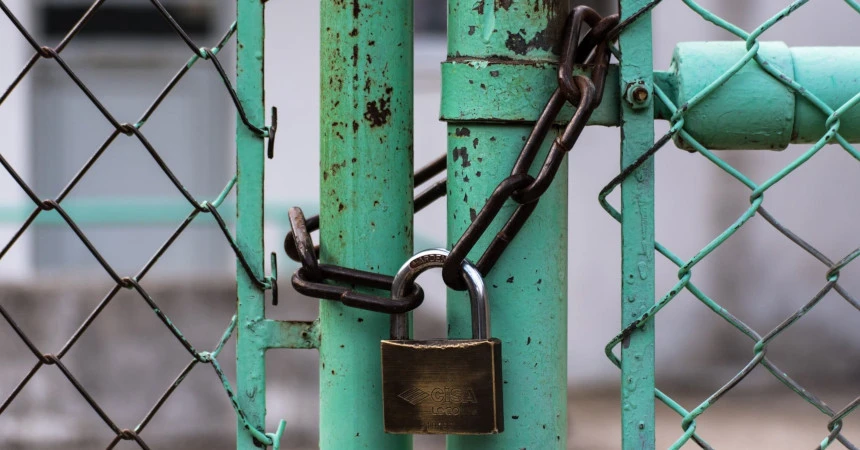 A padlock and a chain locking a greenish fence