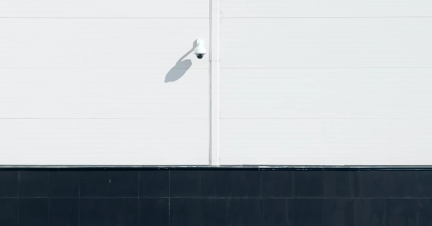 A surveillance camera on a white wall.