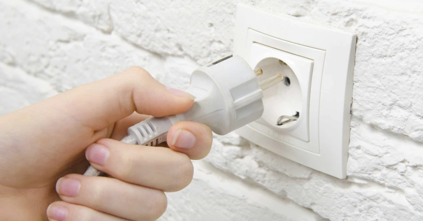 Hand pulling a plug from the power outlet
