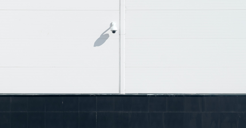 A surveillance camera on a white wall.